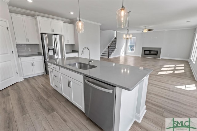 kitchen featuring stainless steel appliances, dark countertops, open floor plan, white cabinets, and a sink