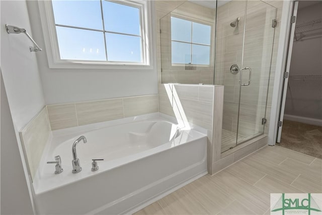 full bathroom featuring a garden tub, a spacious closet, and a shower stall