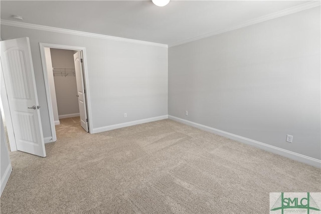 unfurnished bedroom featuring light carpet, a spacious closet, baseboards, and crown molding