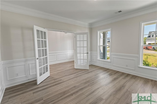 empty room with ornamental molding, french doors, visible vents, and light wood-style flooring