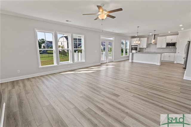 unfurnished living room featuring visible vents, baseboards, light wood-style flooring, ornamental molding, and ceiling fan with notable chandelier