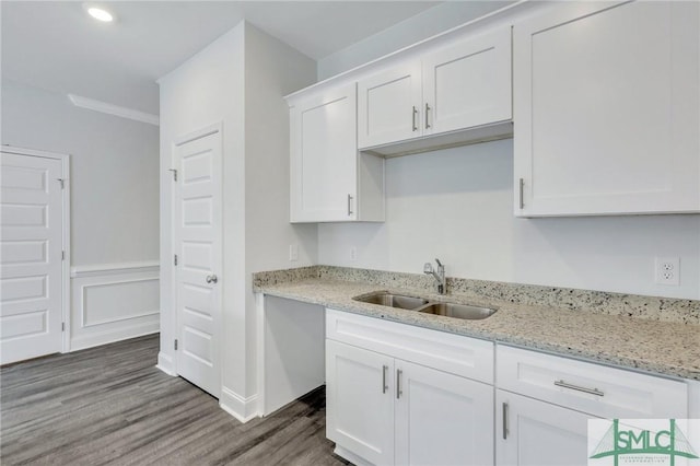 kitchen with sink, light stone counters, ornamental molding, white cabinets, and dark hardwood / wood-style flooring