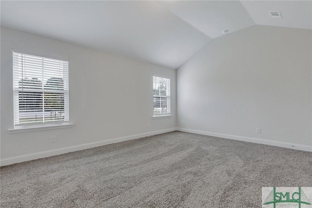 carpeted empty room with vaulted ceiling