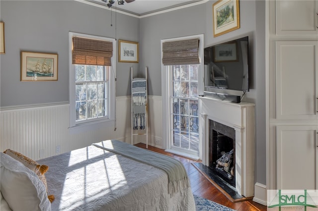 bedroom featuring dark hardwood / wood-style flooring, crown molding, access to outside, and a premium fireplace