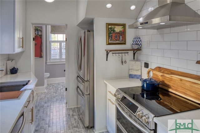 kitchen with white cabinets, stainless steel appliances, wall chimney range hood, tasteful backsplash, and lofted ceiling