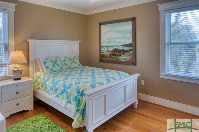 bedroom with multiple windows, crown molding, and light hardwood / wood-style flooring