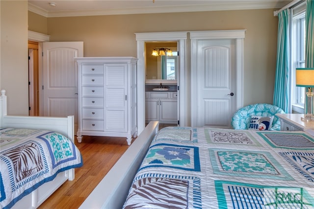 bedroom featuring multiple windows, ornamental molding, light hardwood / wood-style flooring, and sink