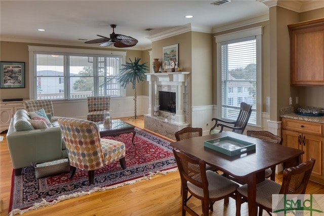 living room with a fireplace, ornamental molding, light hardwood / wood-style floors, and ceiling fan