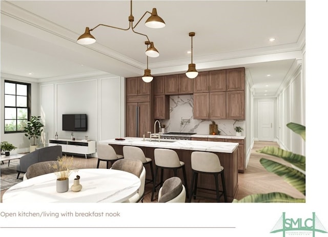 kitchen featuring hanging light fixtures, sink, a center island with sink, a chandelier, and ornamental molding