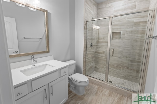 bathroom featuring vanity, a shower with shower door, and toilet