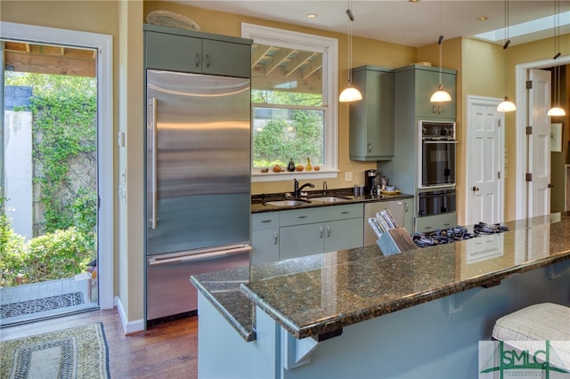 kitchen featuring stainless steel built in fridge, sink, dark hardwood / wood-style floors, and a breakfast bar area