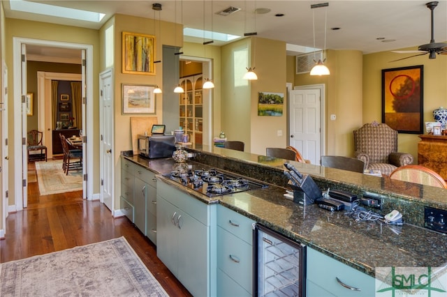 kitchen featuring ceiling fan, gas cooktop, beverage cooler, and dark wood-type flooring