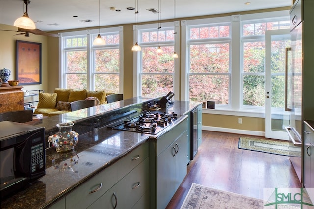 kitchen featuring dark hardwood / wood-style flooring, a wealth of natural light, stainless steel gas cooktop, and pendant lighting