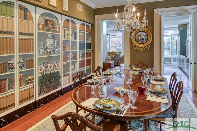 dining space with light hardwood / wood-style flooring, ornamental molding, a chandelier, and a healthy amount of sunlight