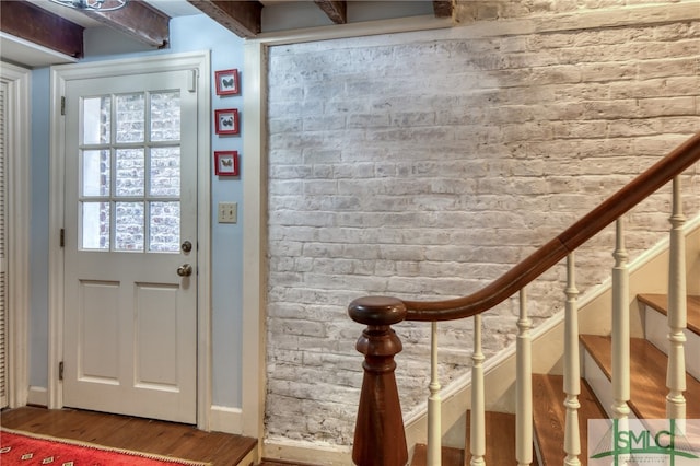 interior space featuring brick wall and dark wood-type flooring