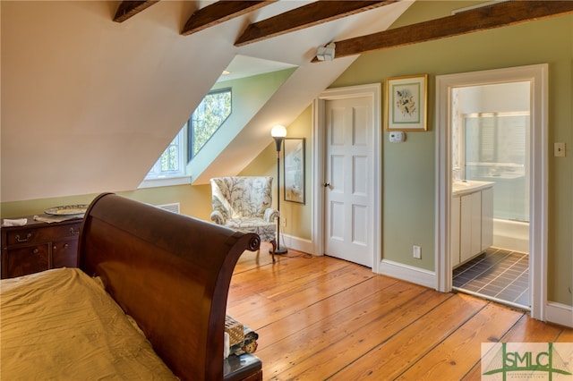 bedroom with vaulted ceiling with beams, connected bathroom, and light tile flooring