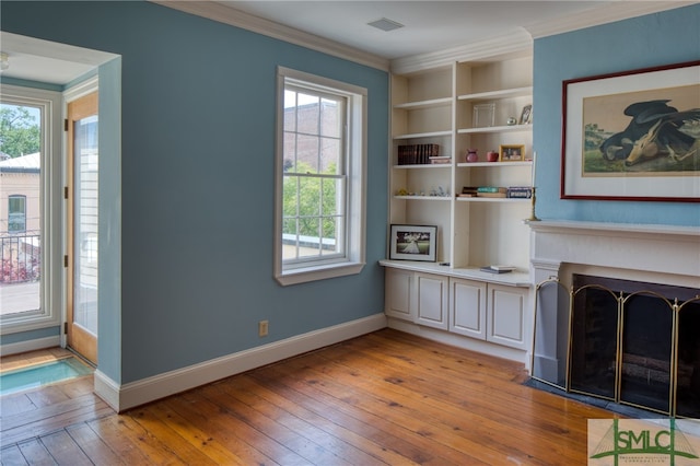 unfurnished living room featuring crown molding, built in features, and light hardwood / wood-style floors