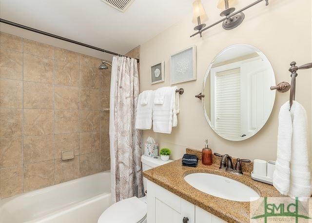 full bathroom featuring toilet, shower / bathtub combination with curtain, vanity, and visible vents
