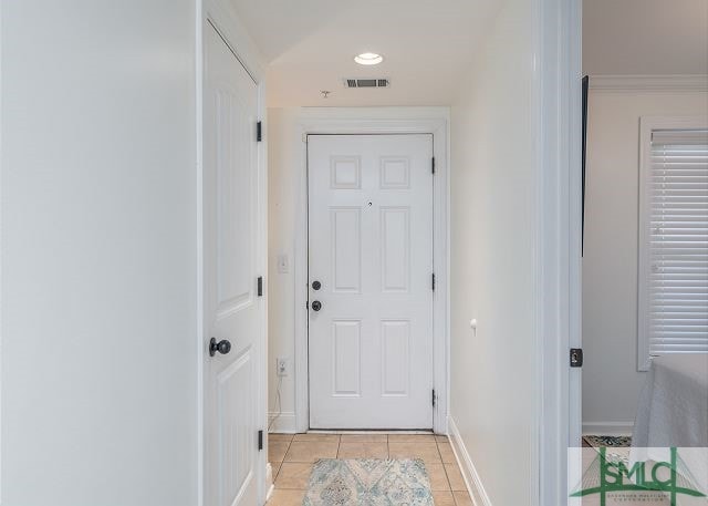 entryway featuring baseboards, ornamental molding, visible vents, and light tile patterned floors
