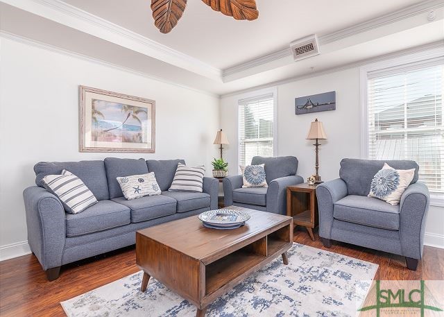 living room with baseboards, visible vents, wood finished floors, and ornamental molding