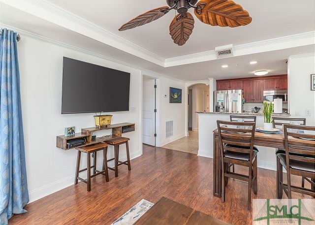 dining room featuring crown molding, visible vents, arched walkways, ceiling fan, and dark wood-style flooring