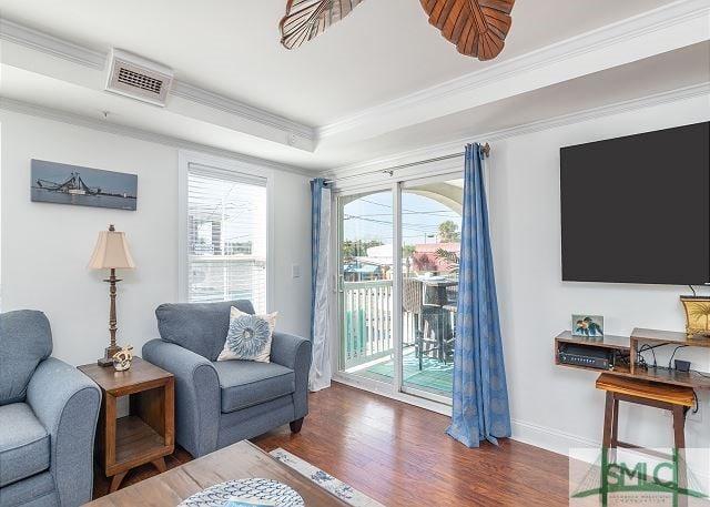 sitting room featuring crown molding, a tray ceiling, baseboards, visible vents, and wood finished floors