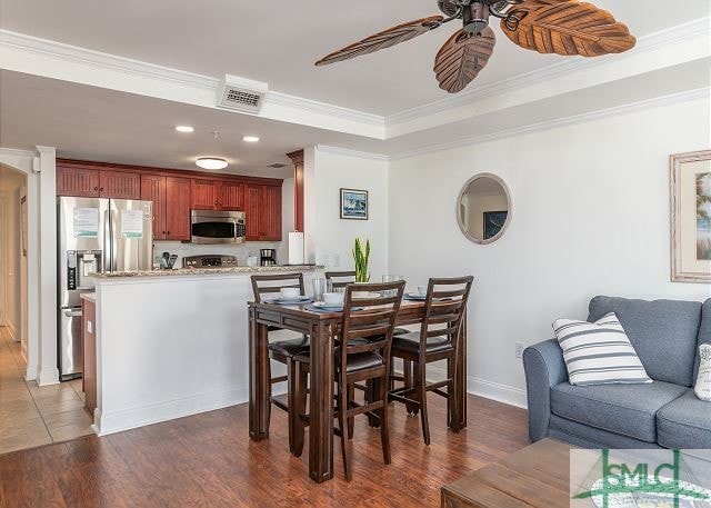 dining area with visible vents, ceiling fan, wood finished floors, and ornamental molding