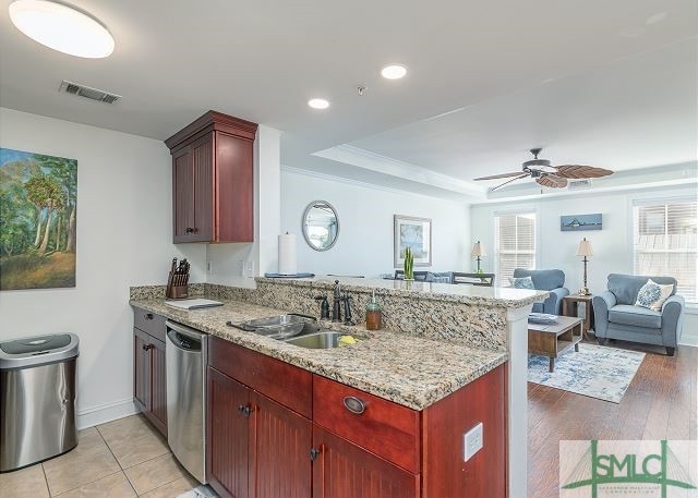 kitchen featuring visible vents, a peninsula, dishwasher, a ceiling fan, and a sink