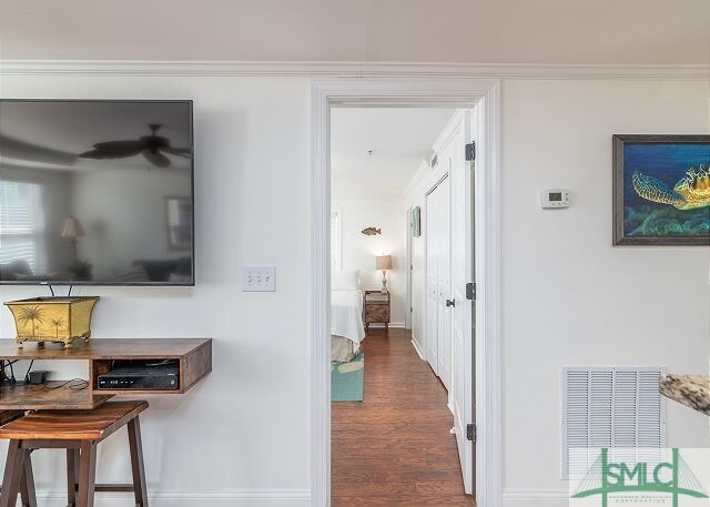 hallway featuring wood finished floors, crown molding, baseboards, and visible vents