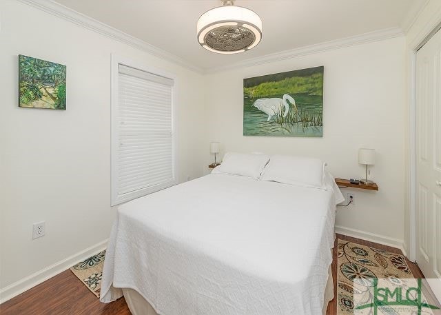 bedroom with crown molding, baseboards, and wood finished floors