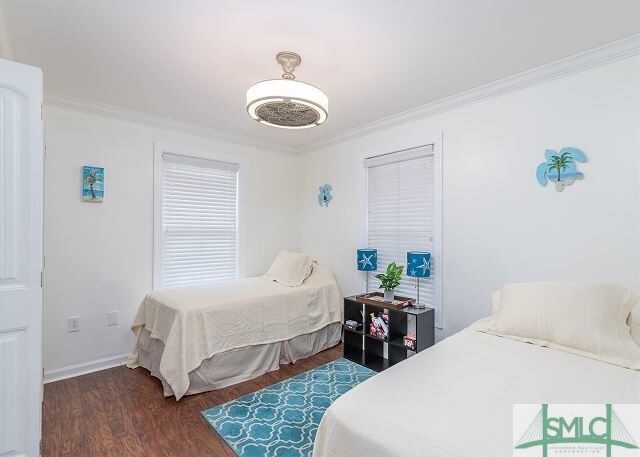 bedroom with dark wood-style floors, baseboards, and crown molding