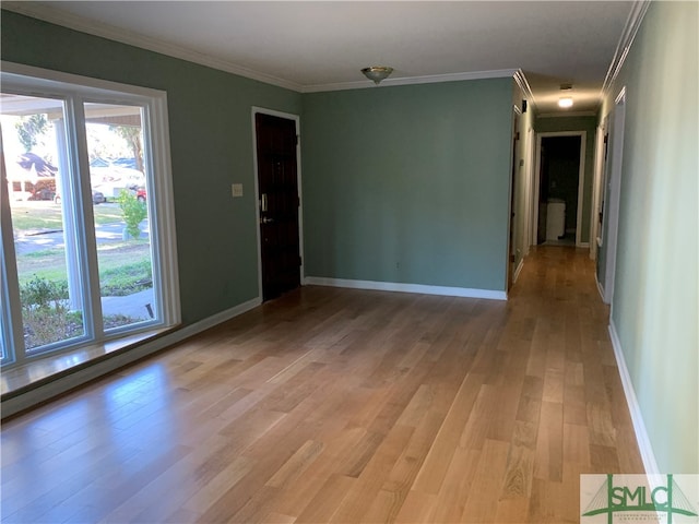 empty room featuring light wood-type flooring and crown molding