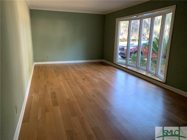 spare room with ornamental molding and light hardwood / wood-style flooring