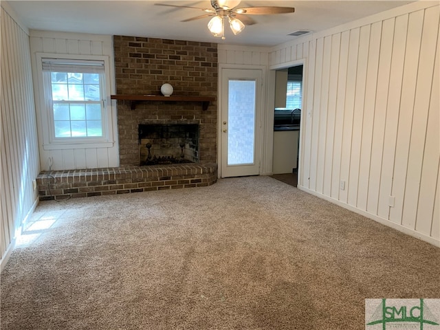 unfurnished living room with ceiling fan, a brick fireplace, and carpet