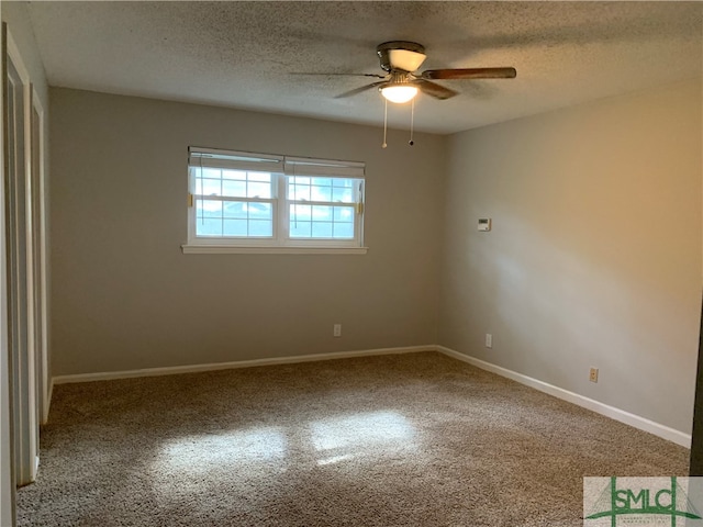 spare room featuring dark colored carpet, ceiling fan, and a textured ceiling