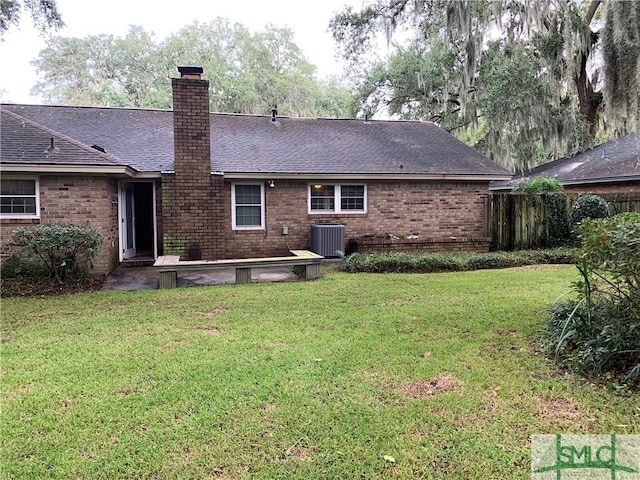 rear view of property featuring central air condition unit and a lawn