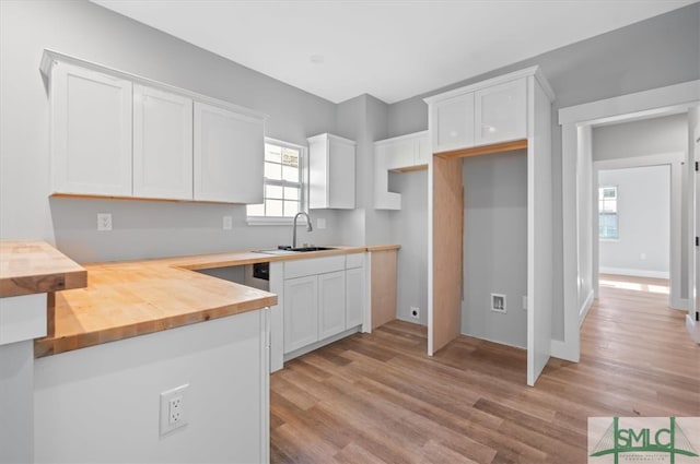 kitchen featuring white cabinets, wooden counters, sink, and light hardwood / wood-style floors