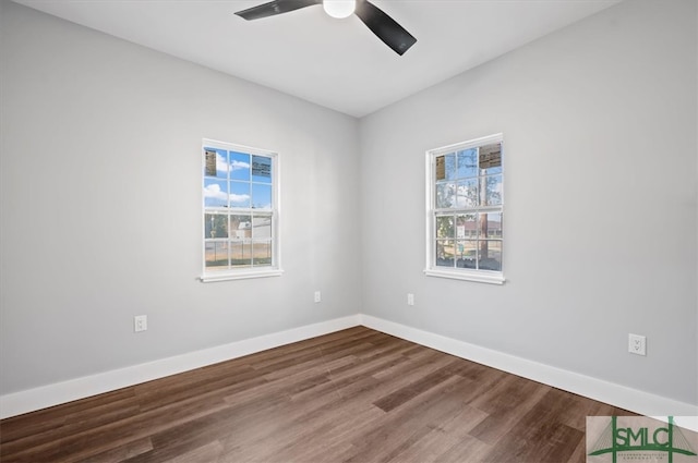 spare room with ceiling fan, a wealth of natural light, and dark wood-type flooring