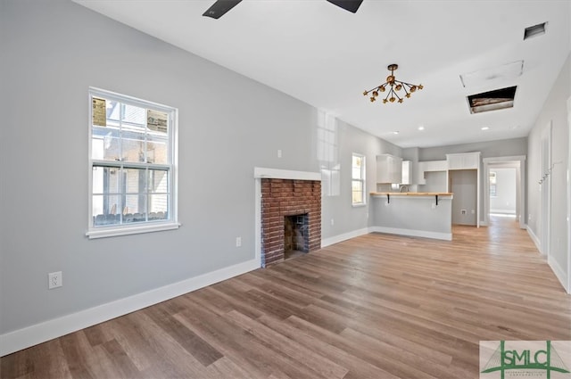 unfurnished living room featuring ceiling fan, a brick fireplace, and light hardwood / wood-style flooring