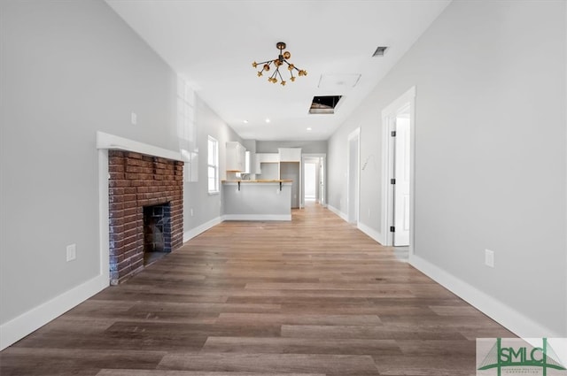 unfurnished living room featuring a chandelier, light hardwood / wood-style floors, and a brick fireplace