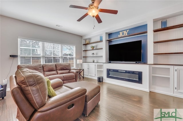 living room with built in features, ceiling fan, and light hardwood / wood-style flooring