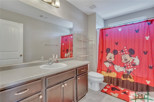 bathroom featuring toilet, vanity, and tile flooring