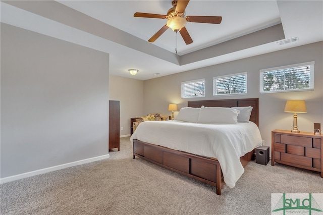 carpeted bedroom featuring ceiling fan and a raised ceiling