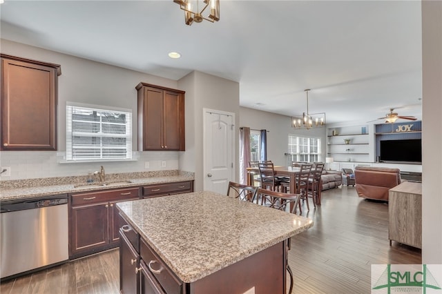 kitchen with decorative light fixtures, ceiling fan with notable chandelier, sink, dishwasher, and a kitchen island