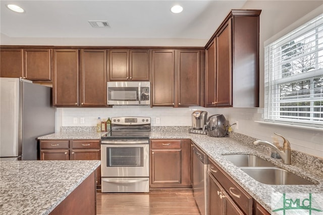 kitchen with sink, stainless steel appliances, light wood-type flooring, and a healthy amount of sunlight