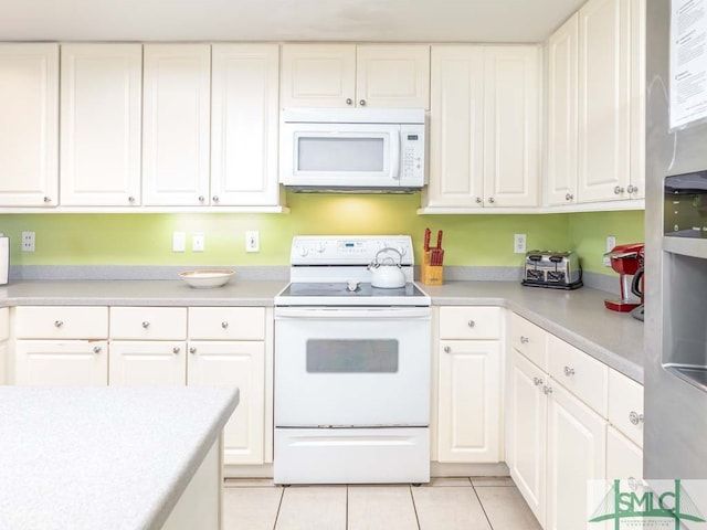kitchen with white appliances, light tile floors, and white cabinets