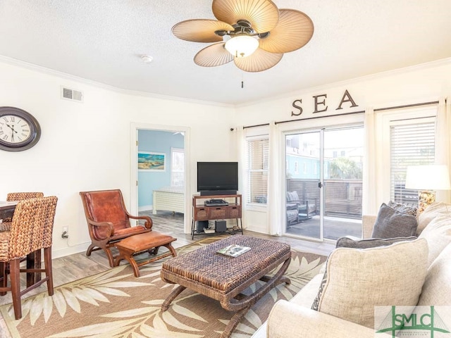 living room featuring light hardwood / wood-style flooring, crown molding, and ceiling fan