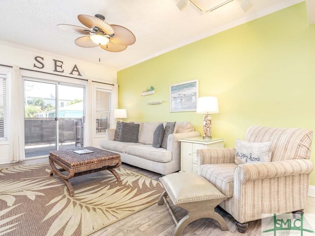 living room featuring ornamental molding, ceiling fan, and light wood-type flooring