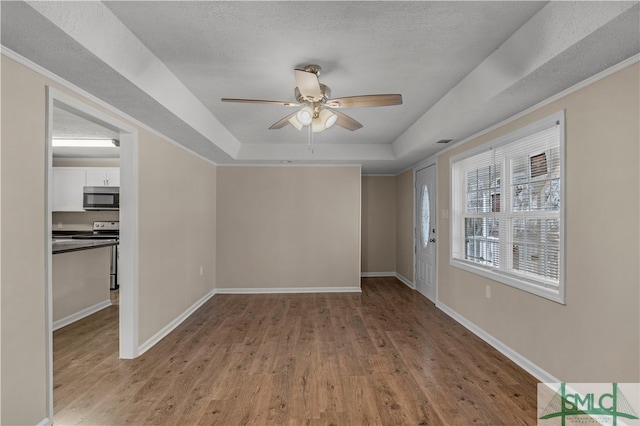 spare room with ceiling fan, a raised ceiling, light hardwood / wood-style floors, and a textured ceiling