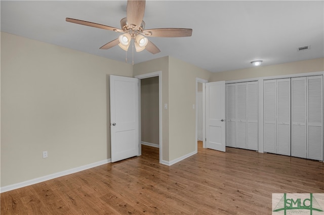 unfurnished bedroom featuring multiple closets, light hardwood / wood-style floors, and ceiling fan